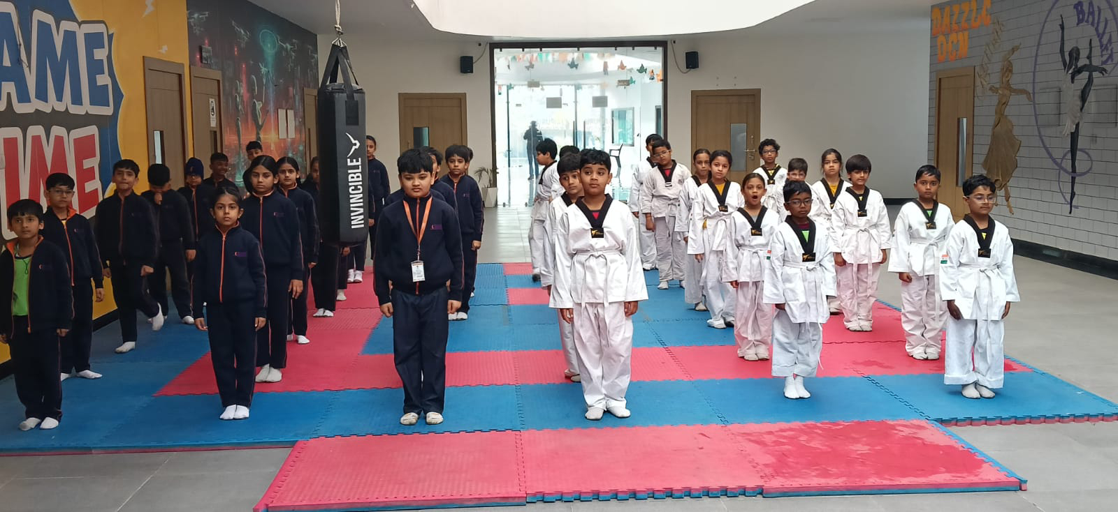 Group of children in karate uniforms standing in formation on colorful mats inside a martial arts studio...